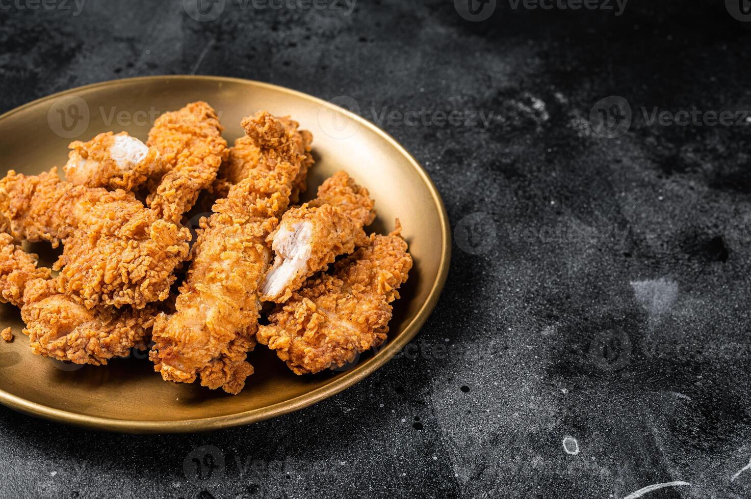 Breaded chicken strips, breast fillet meat on a plate. Black backgrund. Top view. Copy space photo