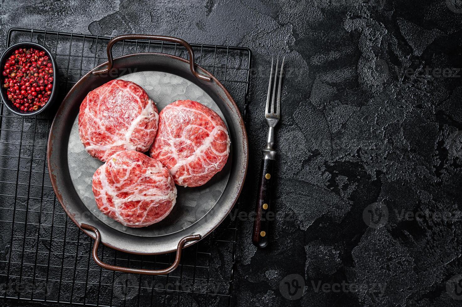 Raw pork cutlet, Crepinette with spices and herbs. Black background. Top view. Copy space photo