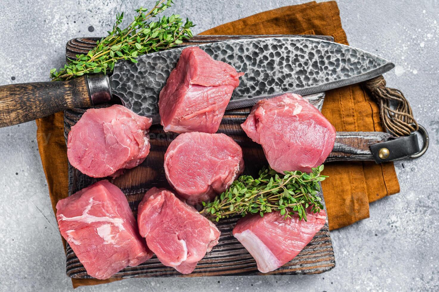 Fresh Raw pork tenderloin medallions steaks on a wooden cutting board. Gray background. Top view photo