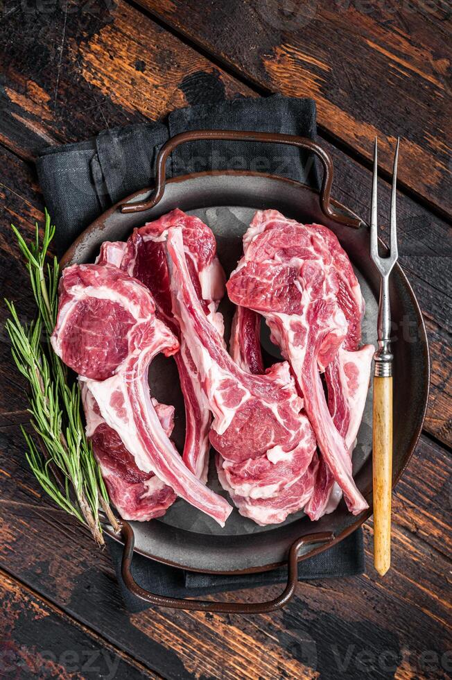 Raw lamb mutton chop steaks, fresh meat cutlets on butcher table. Black background. Top view photo