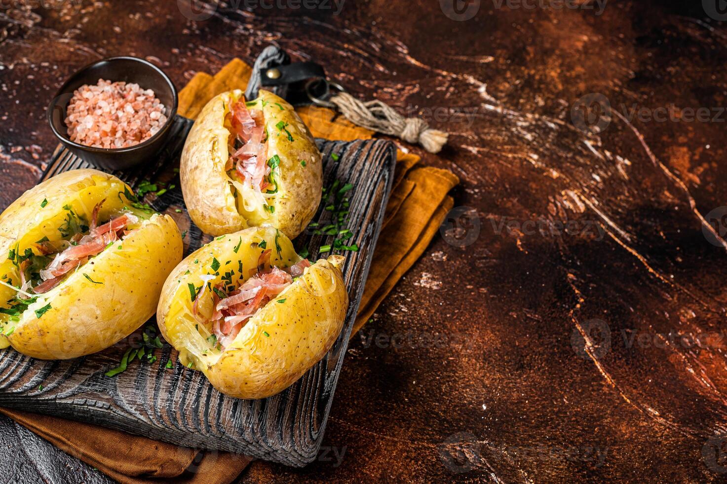 Jacket potatoes baked with cheese, herbs and butter. Dark background. Top view. Copy space photo