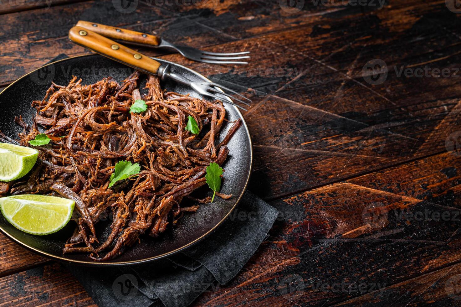 Carnitas in a plate with celery and lime wedges. Wooden background. Top view. Copy space photo