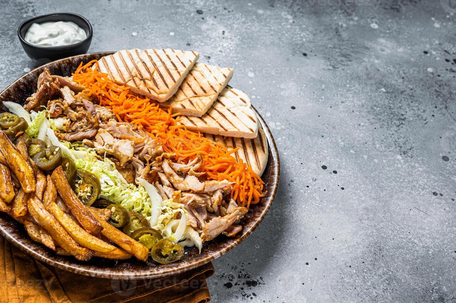 Chicken Shawarma Doner kebab on a plate with french fries, vegetables and salad. Gray background. Top view. Copy space photo