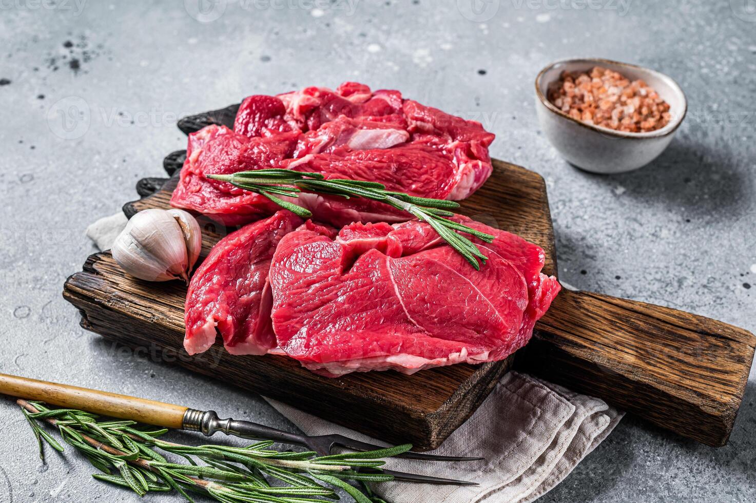 Uncooked Raw Lamb chop leg steaks on cutting board. Gray background. Top view photo
