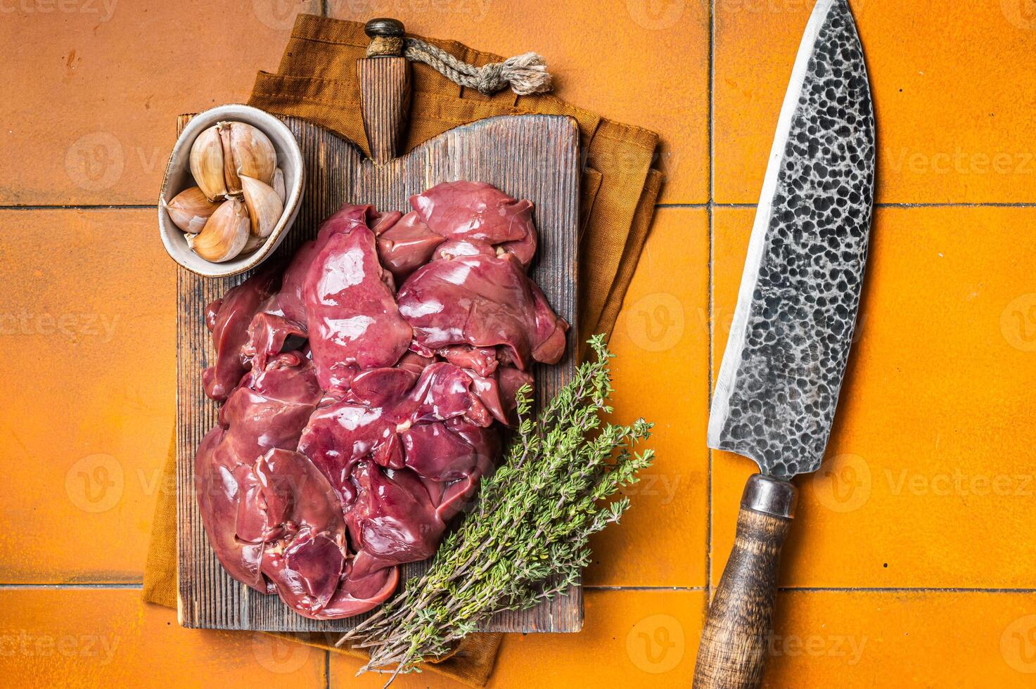 Raw chicken liver, fresh fowl giblets on wooden board. Orange background. Top view photo