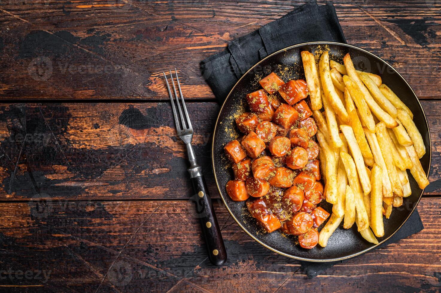 German currywurst meal, curry wurst with french fry served in a plate. Wooden background. Top view. Copy space photo