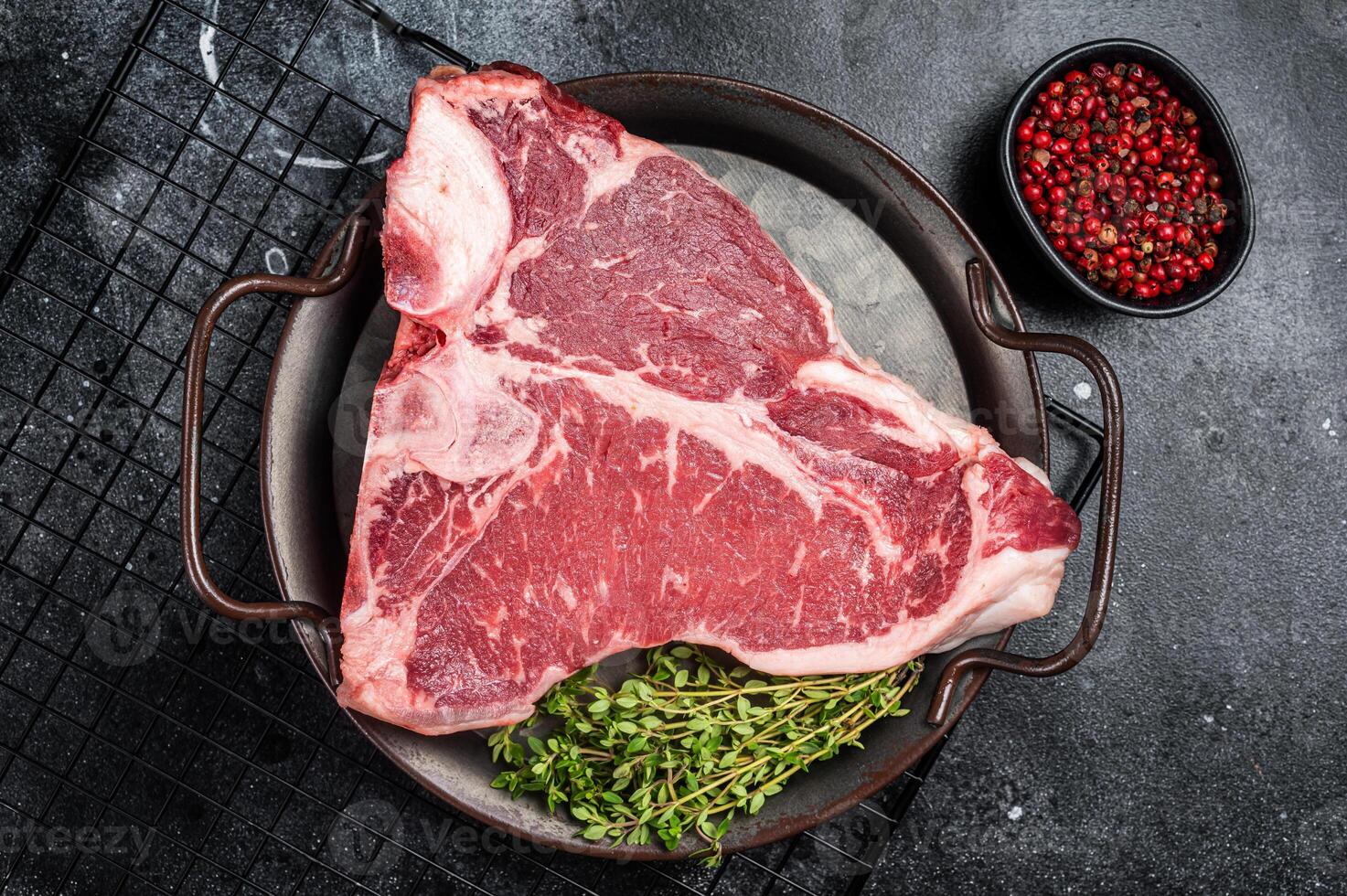 Fresh raw T-bone marbled beef meat Steak on a steel tray. Black background. Top view photo