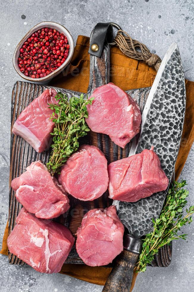 Fresh Raw pork tenderloin medallions steaks on a wooden cutting board. Gray background. Top view photo