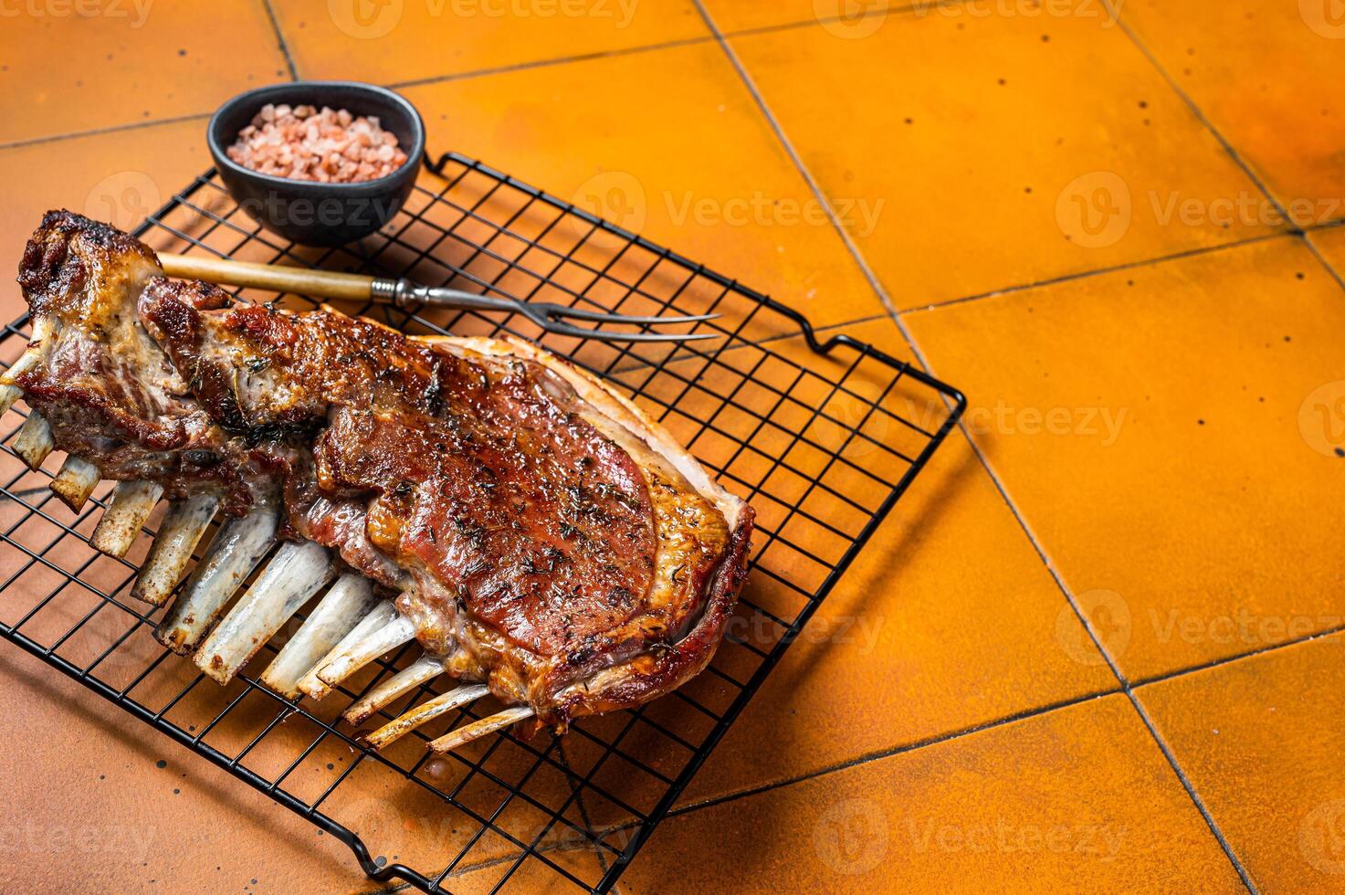 Roast Rack of lamb ribs, spareribs on grill. Orange background. Top view. Copy space photo