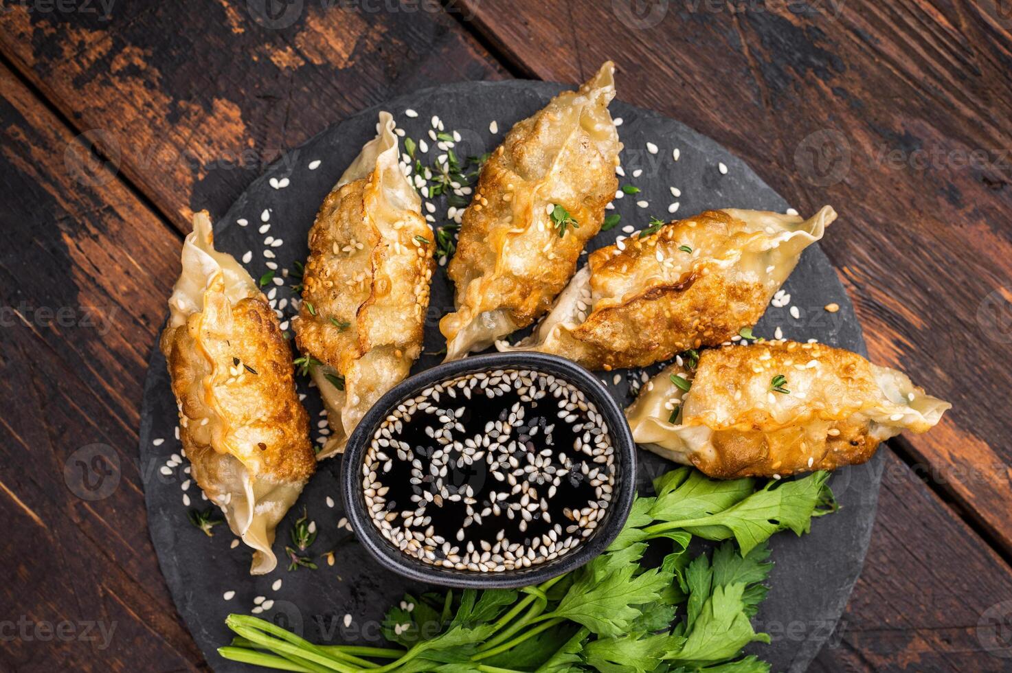Fried Gyoza on plate with sauce, Japanese Dumplings with shrimps and vegetables. wooden background. top view photo