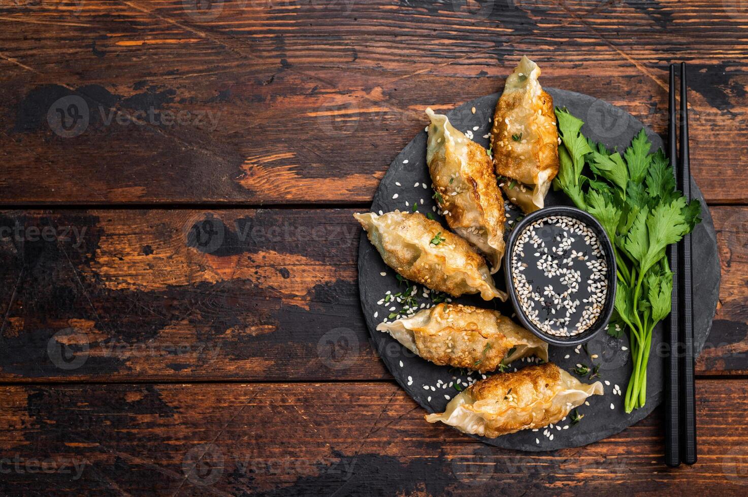 Fried Gyoza on plate with sauce, Japanese Dumplings with shrimps and vegetables. wooden background. top view photo