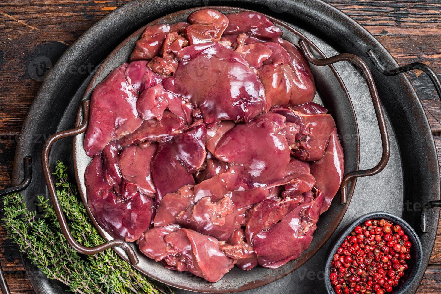 Fresh Raw chicken liver, poultry giblets in steel tray with herbs. Wooden background. Top view photo