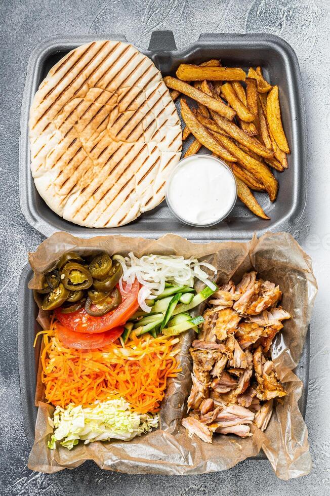 Doner kebab Shawarma on a plate with french fries and salad in box to go, take away. White background. Top view photo
