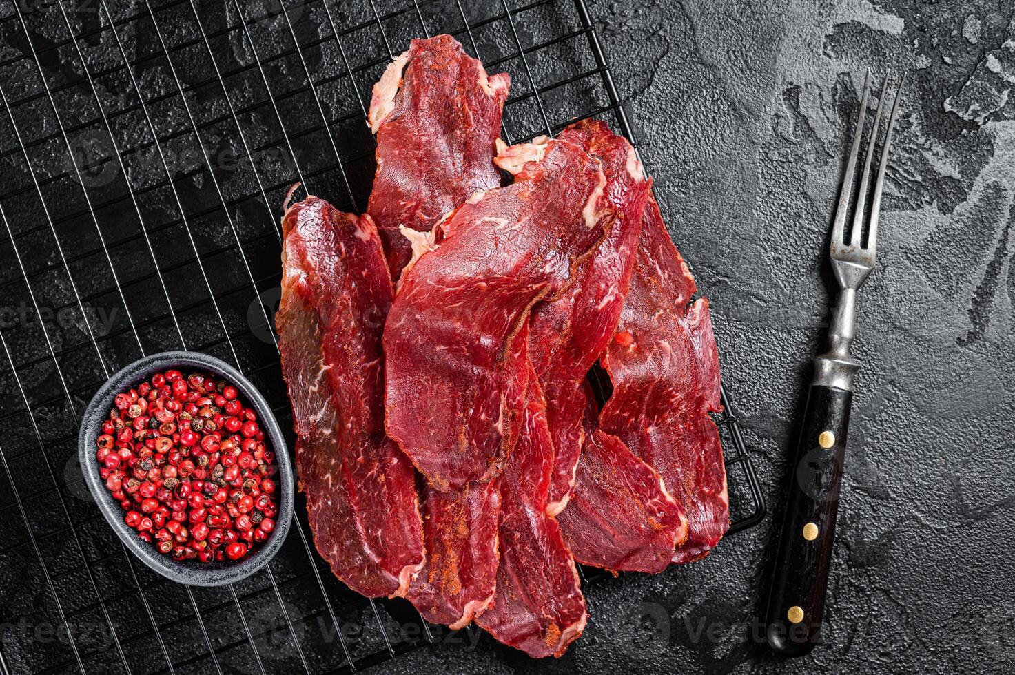 Dried sliced basturma, cured beef meat ready for eat. Black background. Top view photo