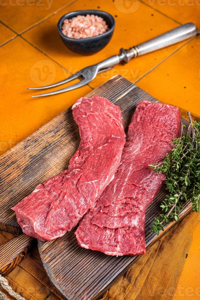 Butcher table with Raw lamb tenderloin Fillet, Mutton loin Meat with thyme. Orange background. Top view photo