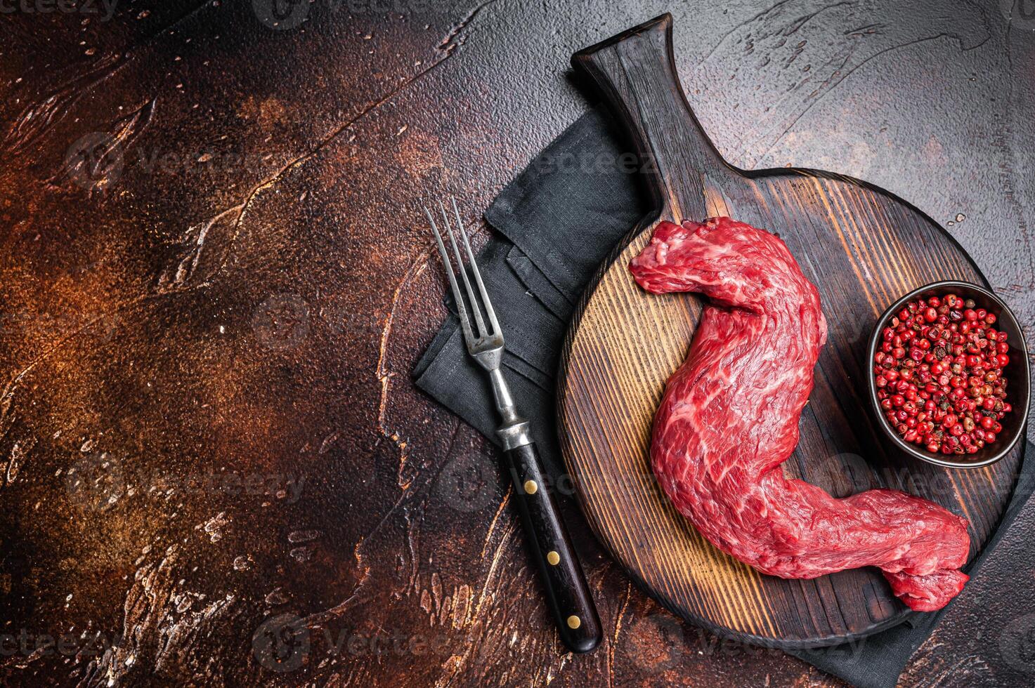 Raw Skirt Machete beef meat steak on wooden board. Dark background. Top view. Copy space photo
