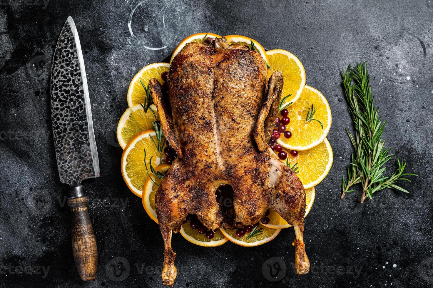 Christmas dinner, baked duck with rosemary and oranges, crispy whole roast duck. Black background. Top view photo