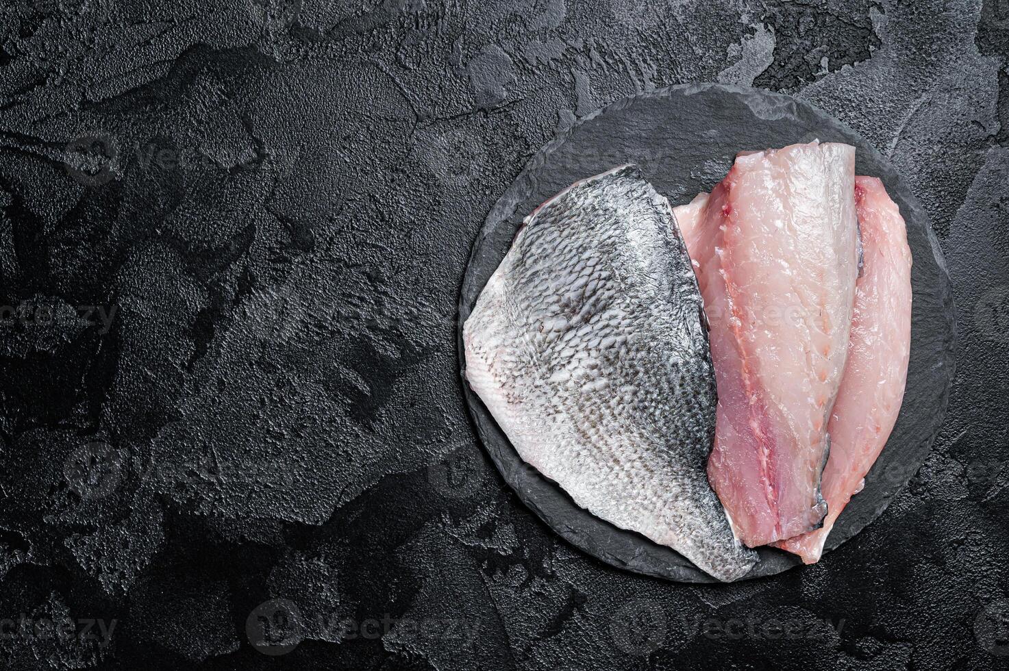 Raw Sea bream Dorado fish fillets. Black background. Top view. Copy space photo