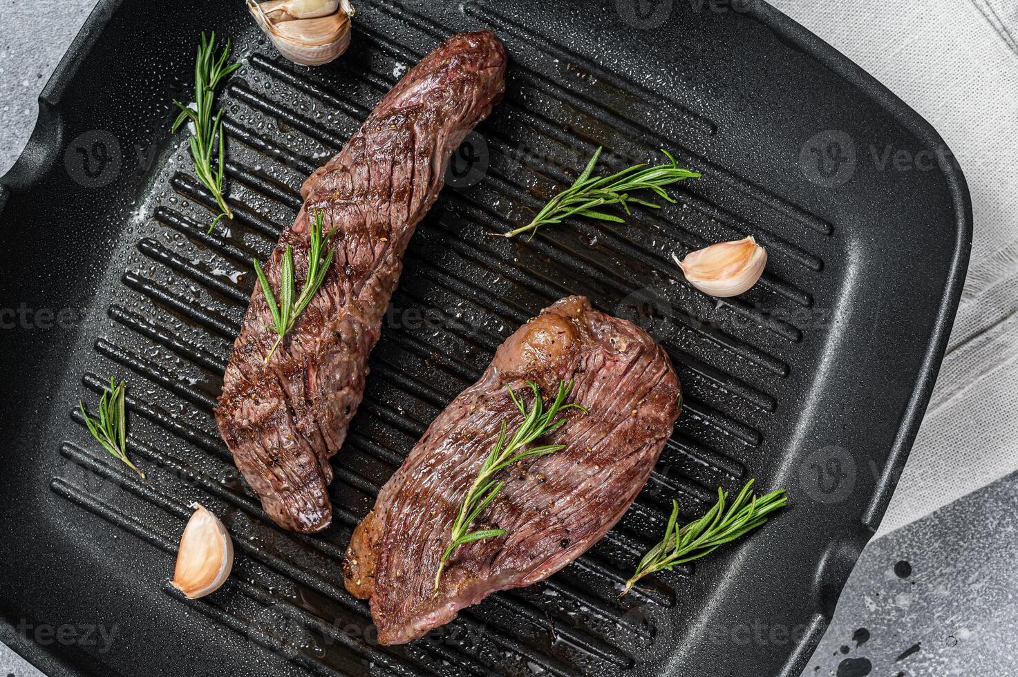 Roasted on a grill skillet Flank flap or Bavette beef meat steak with rosemary. Gray background. Top view photo