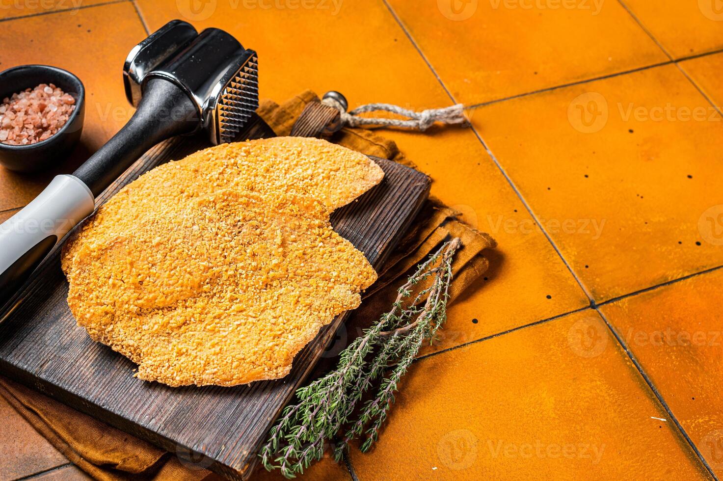 Raw Wiener Schnitzel breaded meat steak. Orange background. Top view. Copy space photo