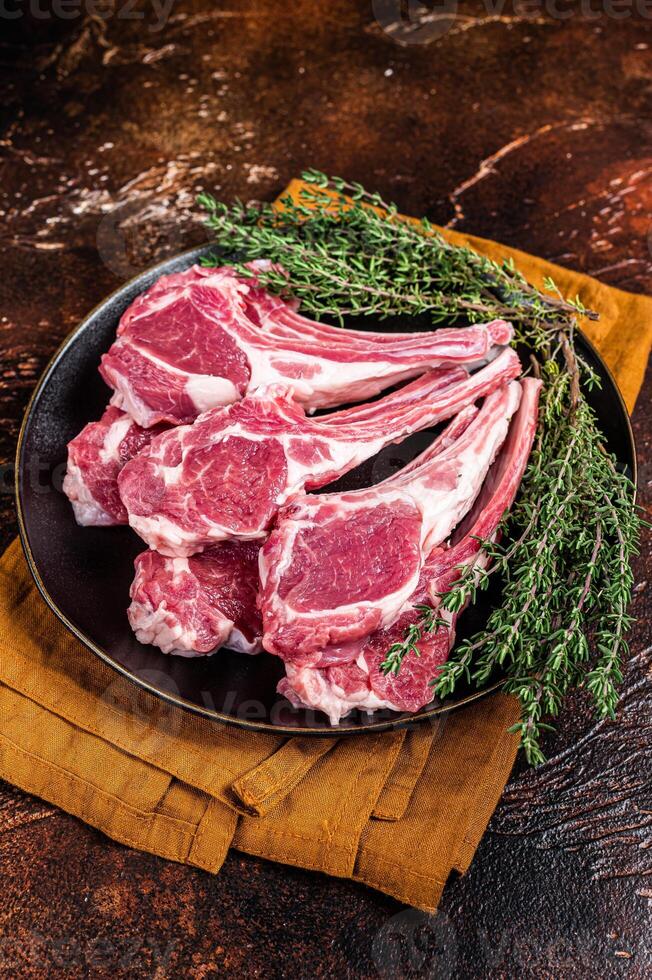 Raw lamb chops, fresh mutton meat cutlets on a ribs. Dark background. Top view photo