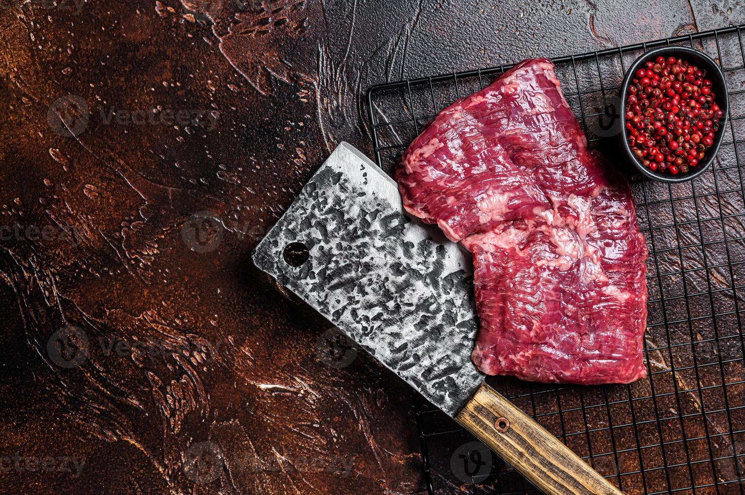 Raw skirt beef steak on meat cleaver. Black background. Top view. Copy space photo