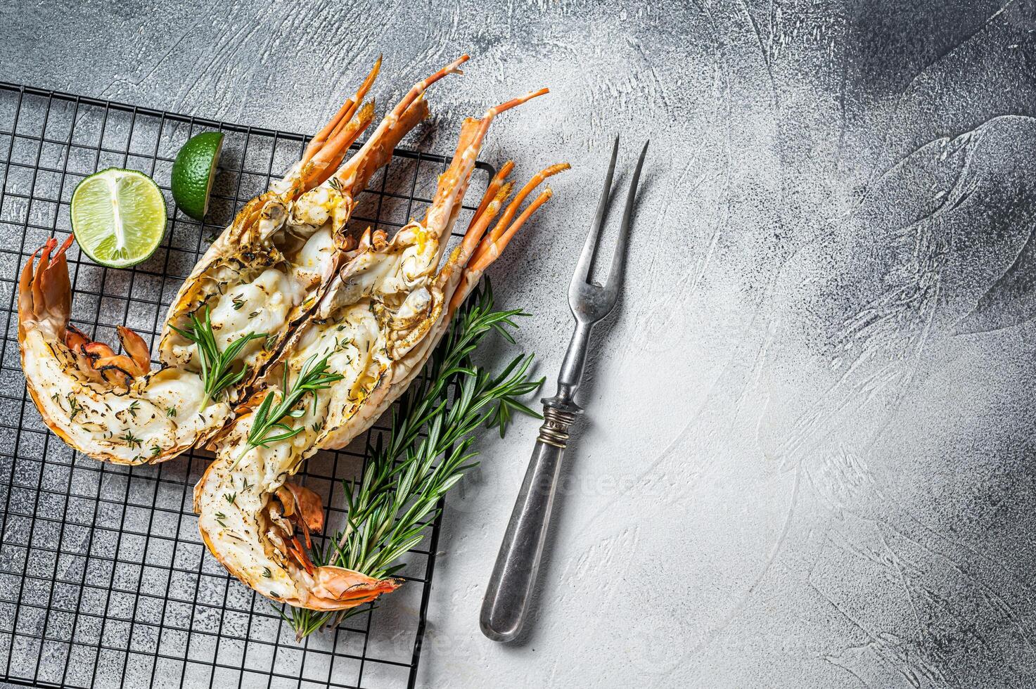 Barbecue grilled and sliced Spiny lobster or sea crayfish with herbs. White background. Top view. Copy space photo
