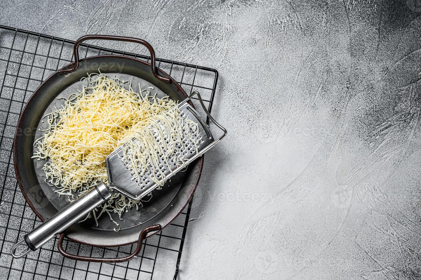 Grated cheese for cooking in a steel tray with grater. White background. Top view. copy space photo
