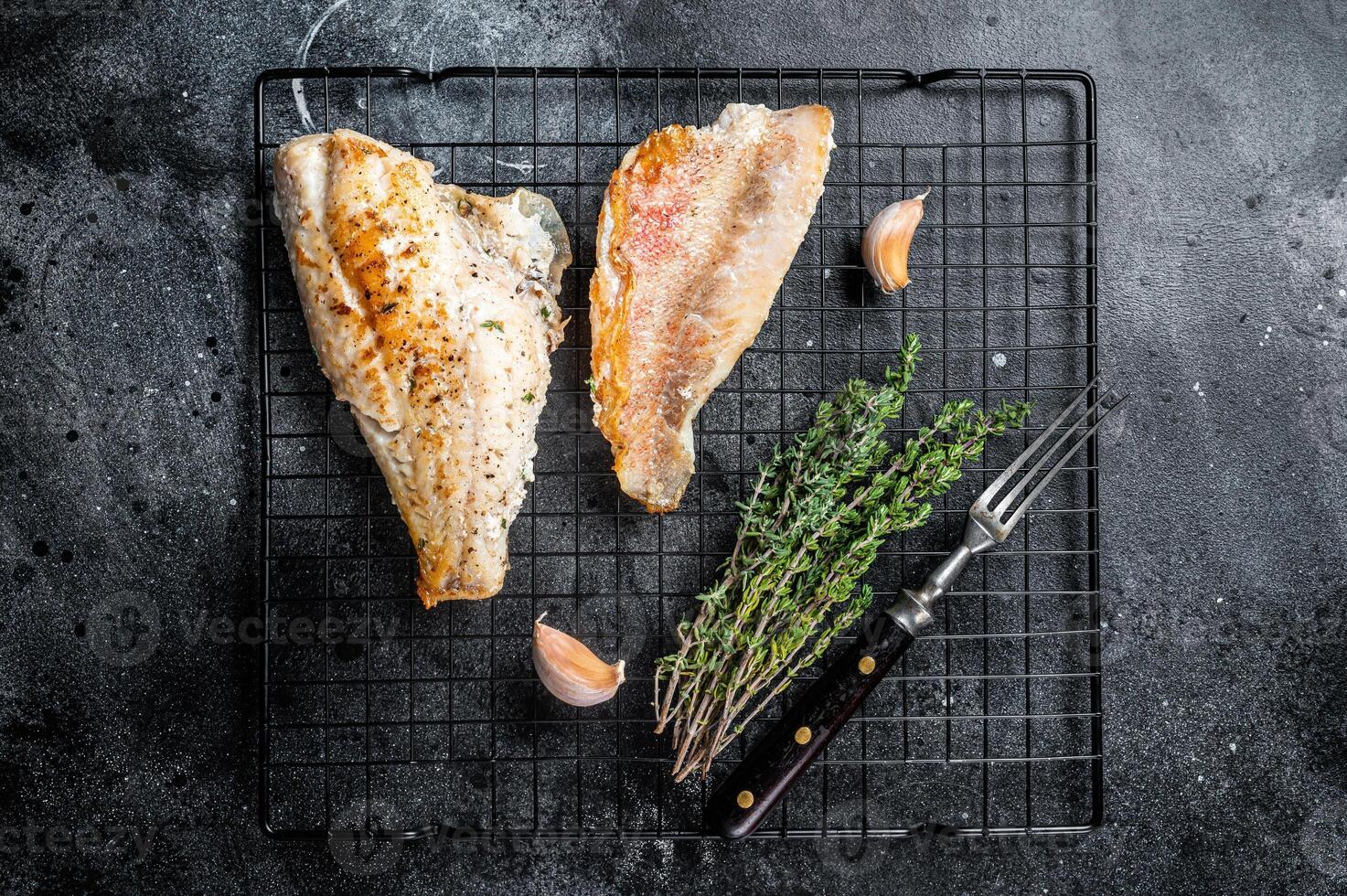 Grilled sea red perch fillet, Snapper fish on a rack. Black background. Top view photo