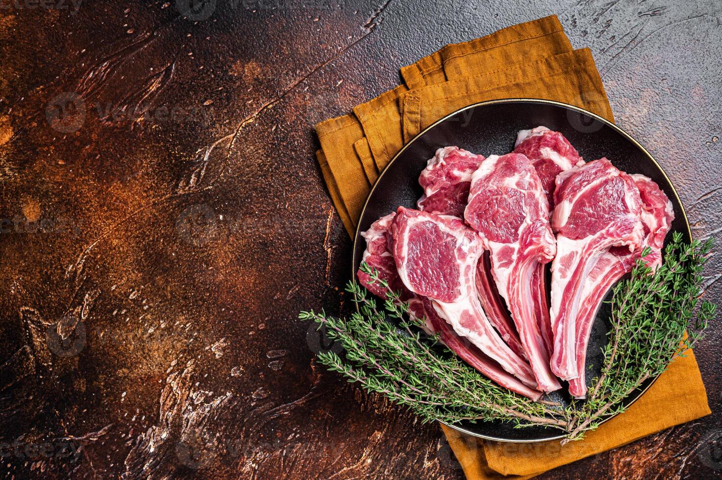Raw lamb chops, fresh mutton meat cutlets on a ribs. Dark background. Top view. Copy space photo