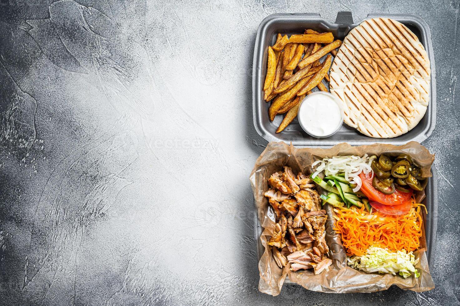 Doner kebab Shawarma on a plate with french fries and salad in box to go, take away. White background. Top view. Copy space photo