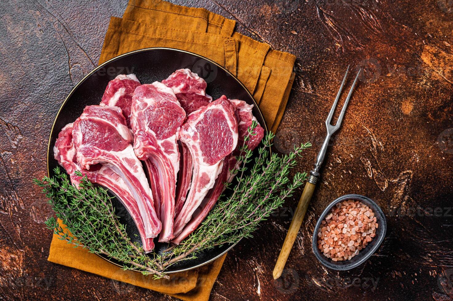 Raw lamb chops, fresh mutton meat cutlets on a ribs. Dark background. Top view photo