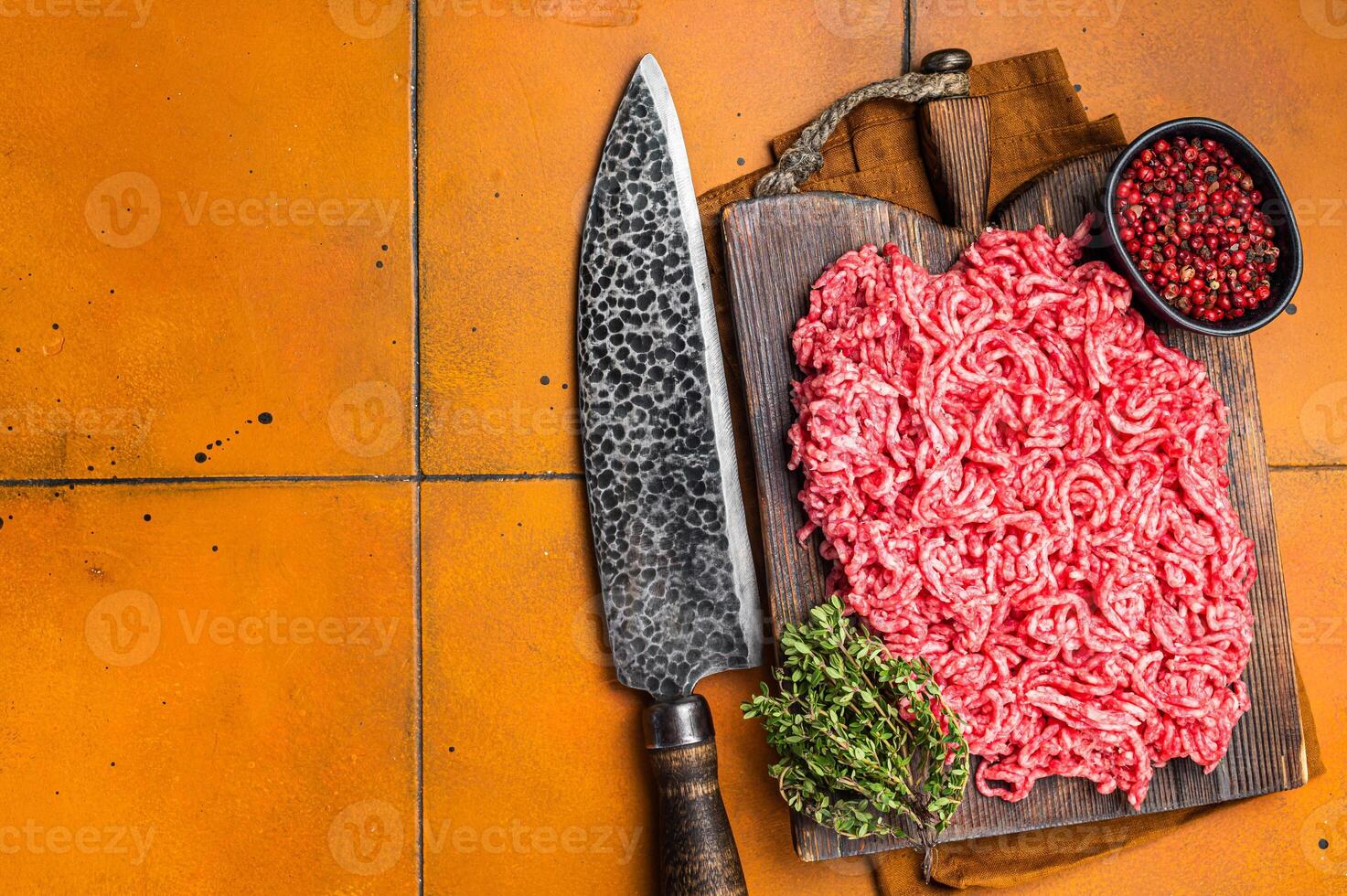 Fresh Raw Mince, Ground beef and pork meat on a butcher board. Orange background. Top view. Copy space photo