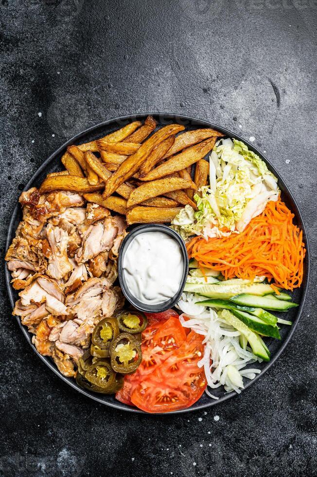 Shawarma Doner kebab on a plate with french fries and salad. Black background. Top view photo