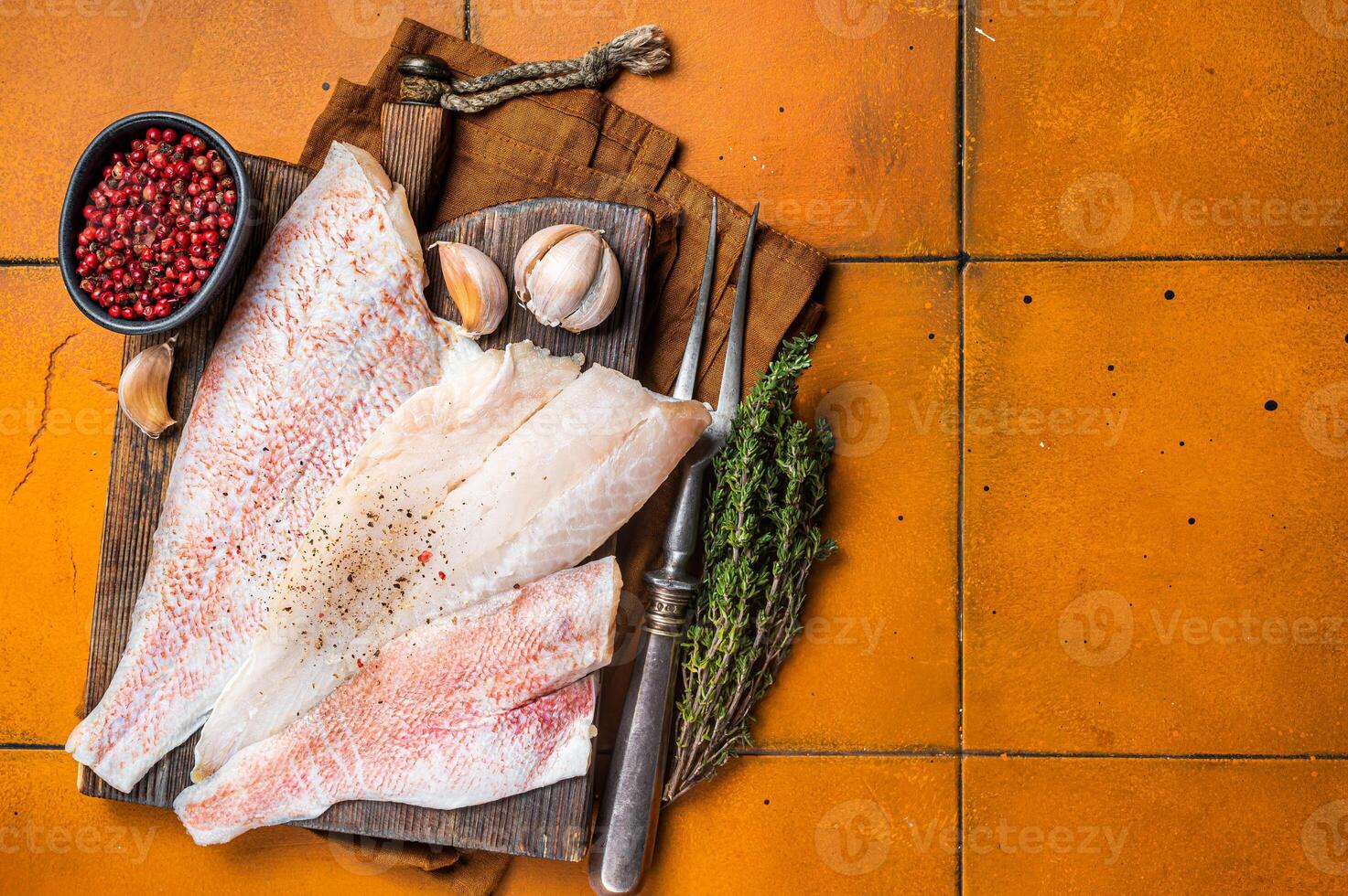 Uncooked ocean red perch fillet, redfish with herbs and spices. Orange background. Top view. Copy space photo