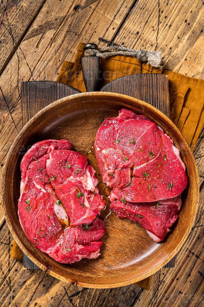 Fresh Mutton chop leg steaks, uncooked lamb meat with herbs. Wooden background. Top view photo