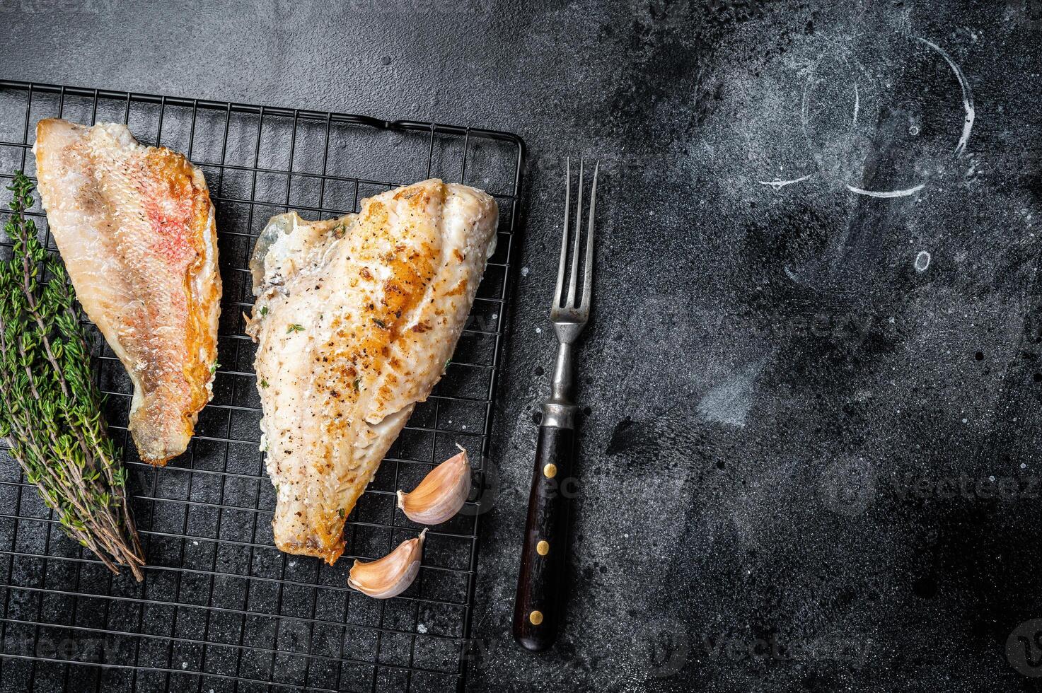 Grilled sea red perch fillet, Snapper fish on a rack. Black background. Top view. Copy space photo
