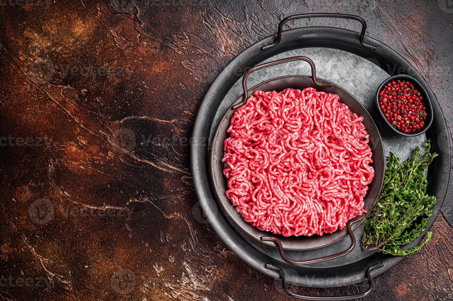 Raw Mince, minced Ground beef meat in a kitchen tray. Dark background. Top view. Copy space photo