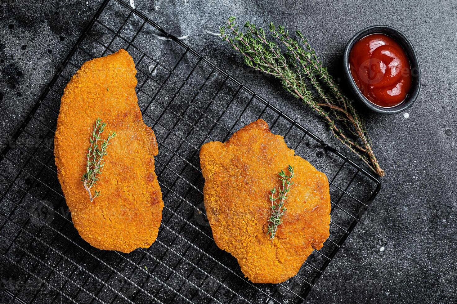 Fried Breaded weiner schnitzel, cooked meat steak. Black background. Top view photo