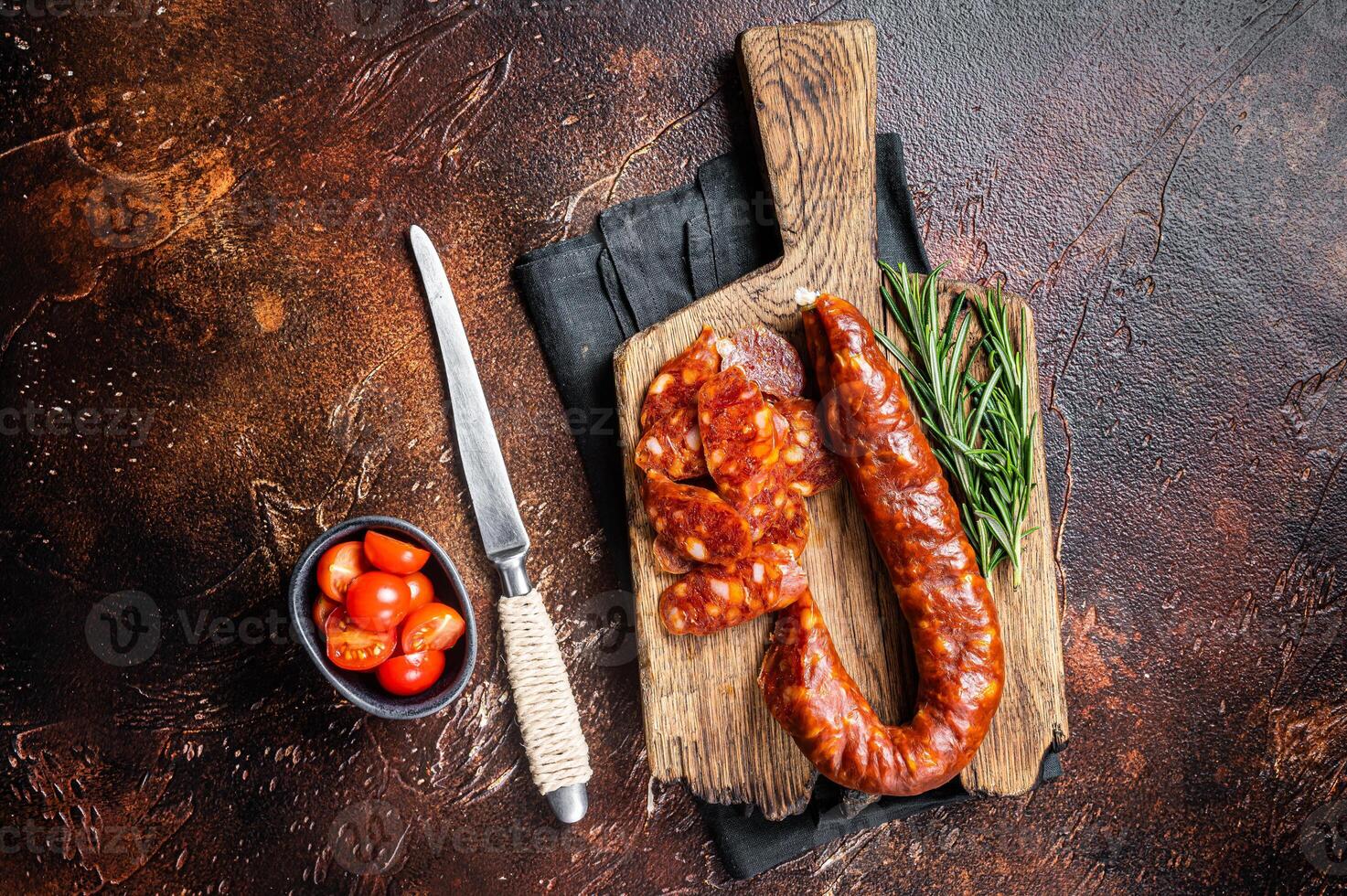 Dry cured Spanish Chorizo sausage, slices of meat with herbs and spices. Dark background. Top view photo