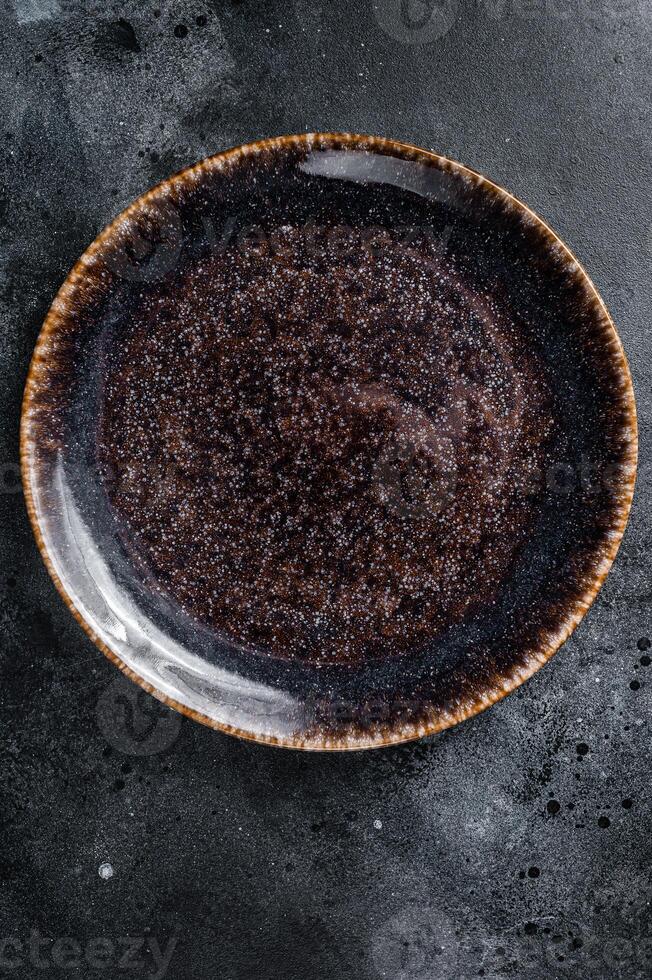 Empty black craft plate on table. Table setting. Black background. Top view. Copy space photo
