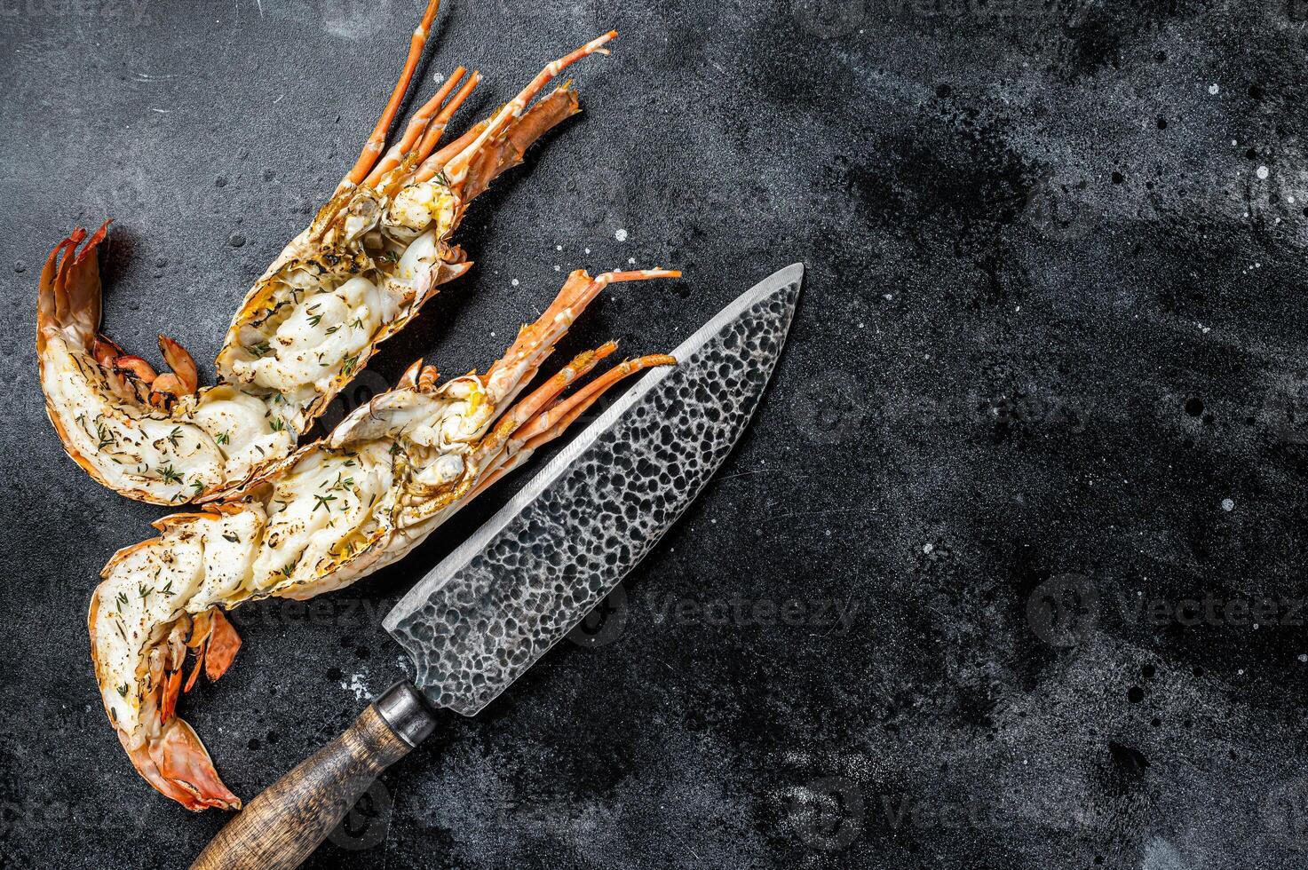 BBQ Grilled Spiny lobster sliced on a cutting board Black background. Top view. Copy space photo