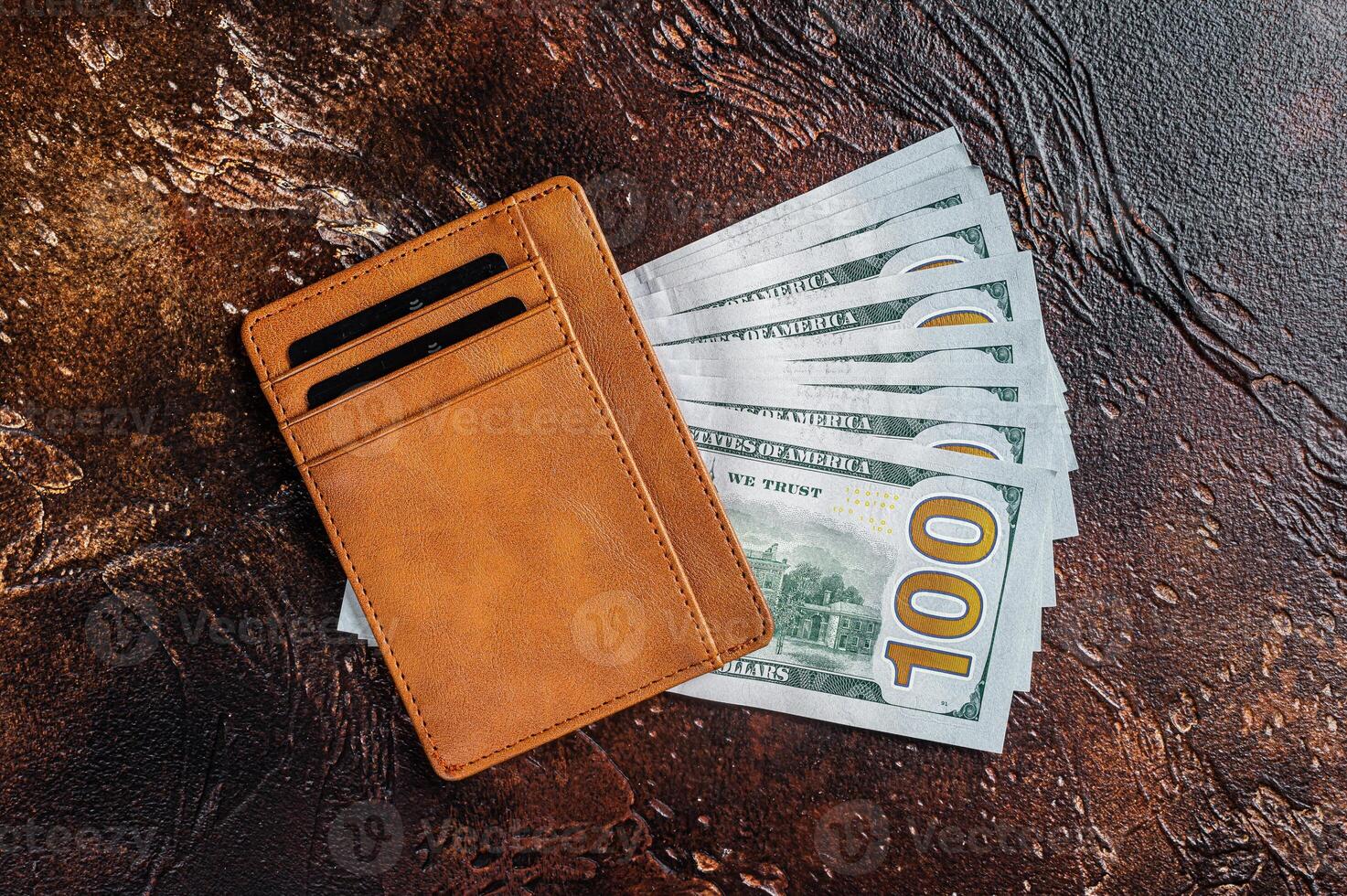 One hundred dollar bill in a brown leather wallet with credit cards. Brown background. Top view. Copy space photo