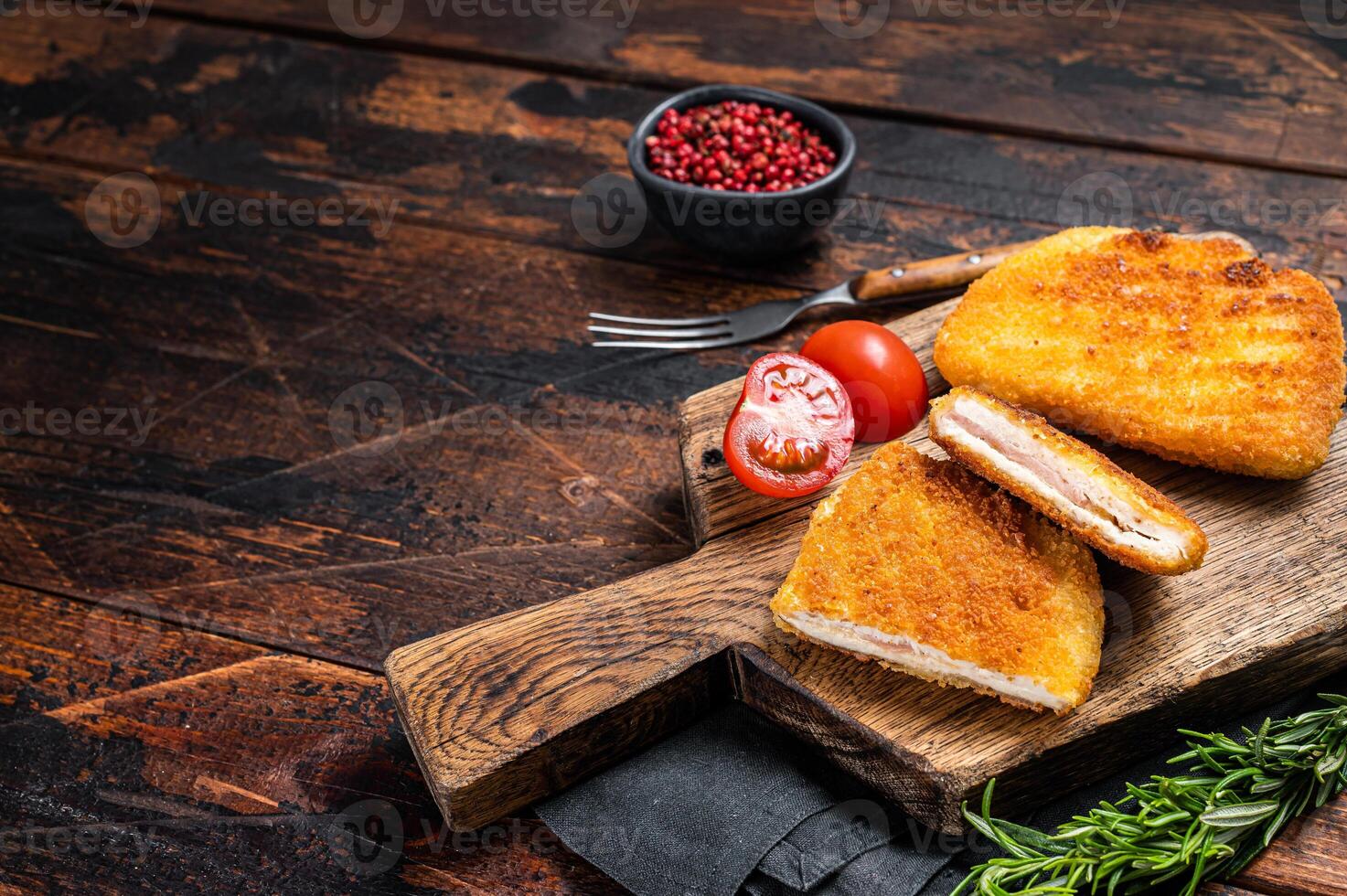 Crispy Cordon Blue Chicken fillet roll with ham and cheese served on a wooden board. Wooden background. Top view. Copy space photo