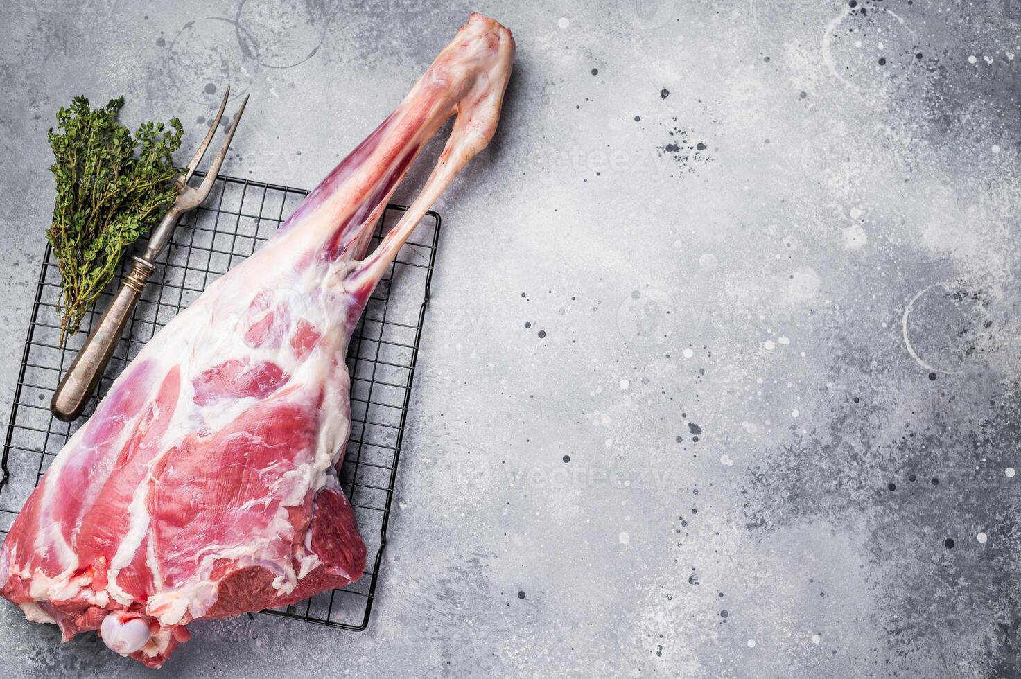 Raw whole lamb leg, fresh mutton meat. grey background. top view photo