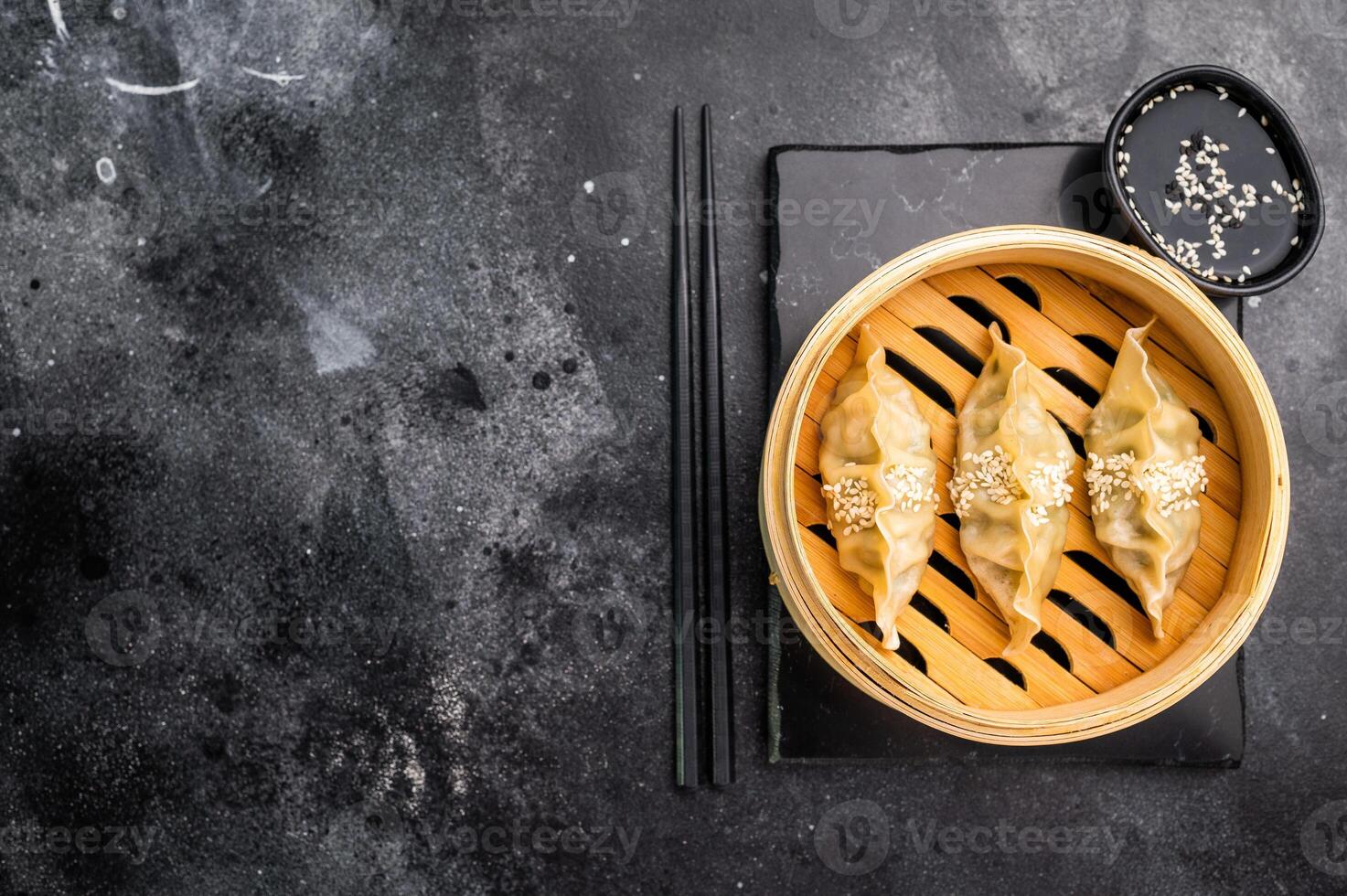 Steamed Japanese Gyoza Dumplings with pork meat and vegetables in bamboo steamer. black background. top view photo