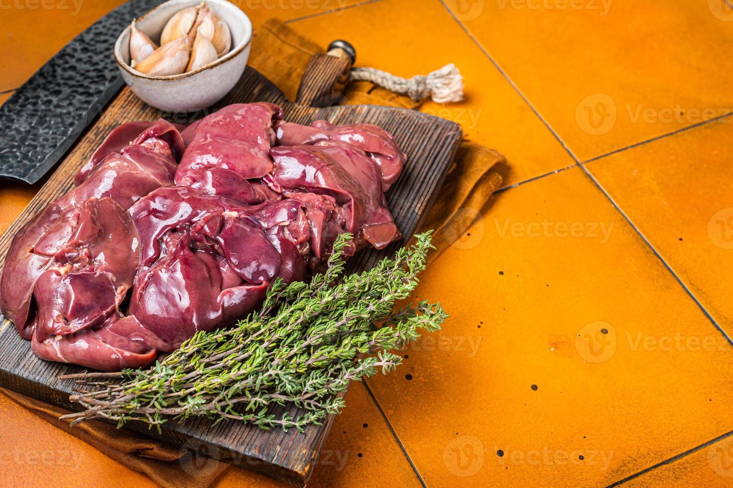Raw chicken liver, fresh fowl giblets on wooden board. Orange background. Top view. Copy space photo