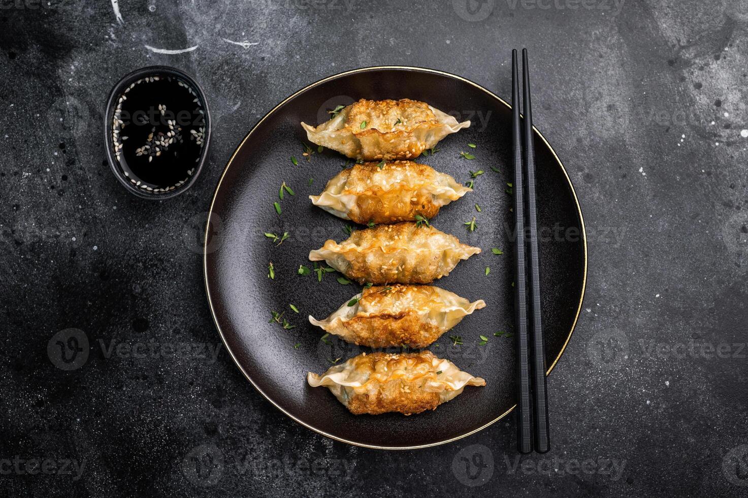 Asian Fried Dumplings, Jiaozi, Gyoza, Dim sum with meat and vegetables on plate. black background. top view photo