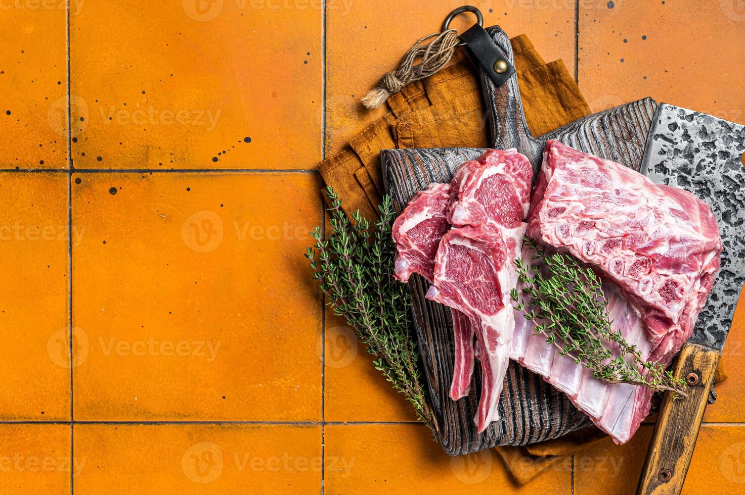 Raw lamb meat chops cutlets on butcher cutting board. Orange background. Top view. Copy space photo