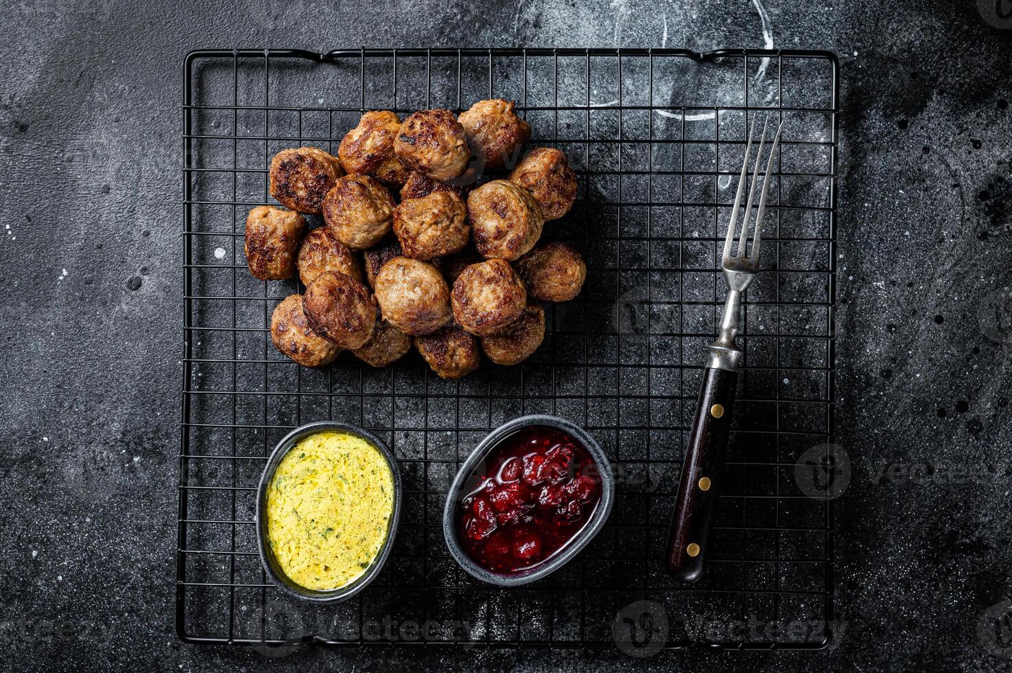 Swedish meatballs with lingonberries and gravy sauce. Black background. Top view photo